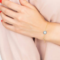 Gold evil eye bracelet with blue round charm on wrist
