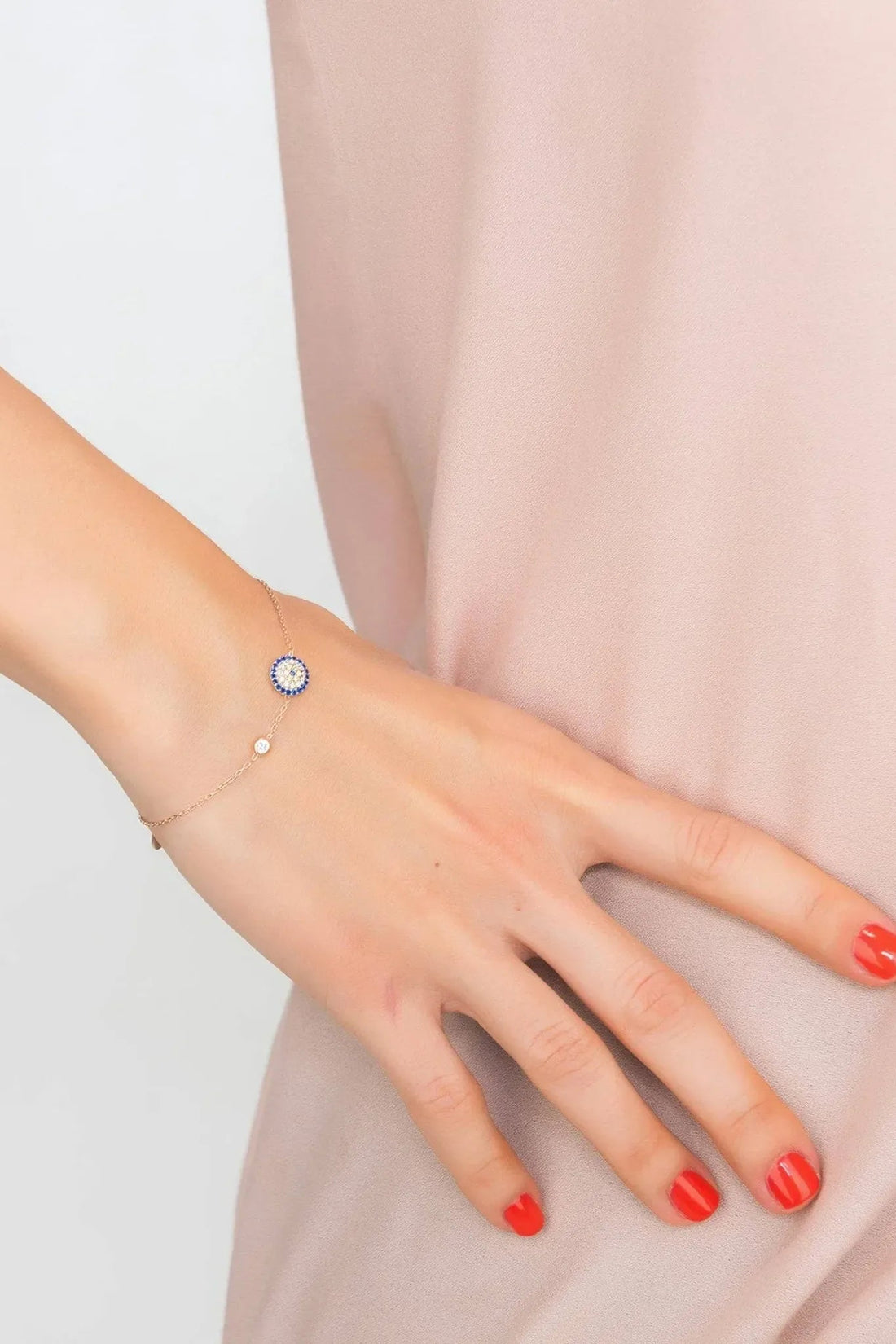 Rose gold evil eye bracelet on wrist with small round blue charm