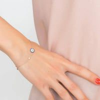Rose gold evil eye bracelet on wrist with small round blue charm