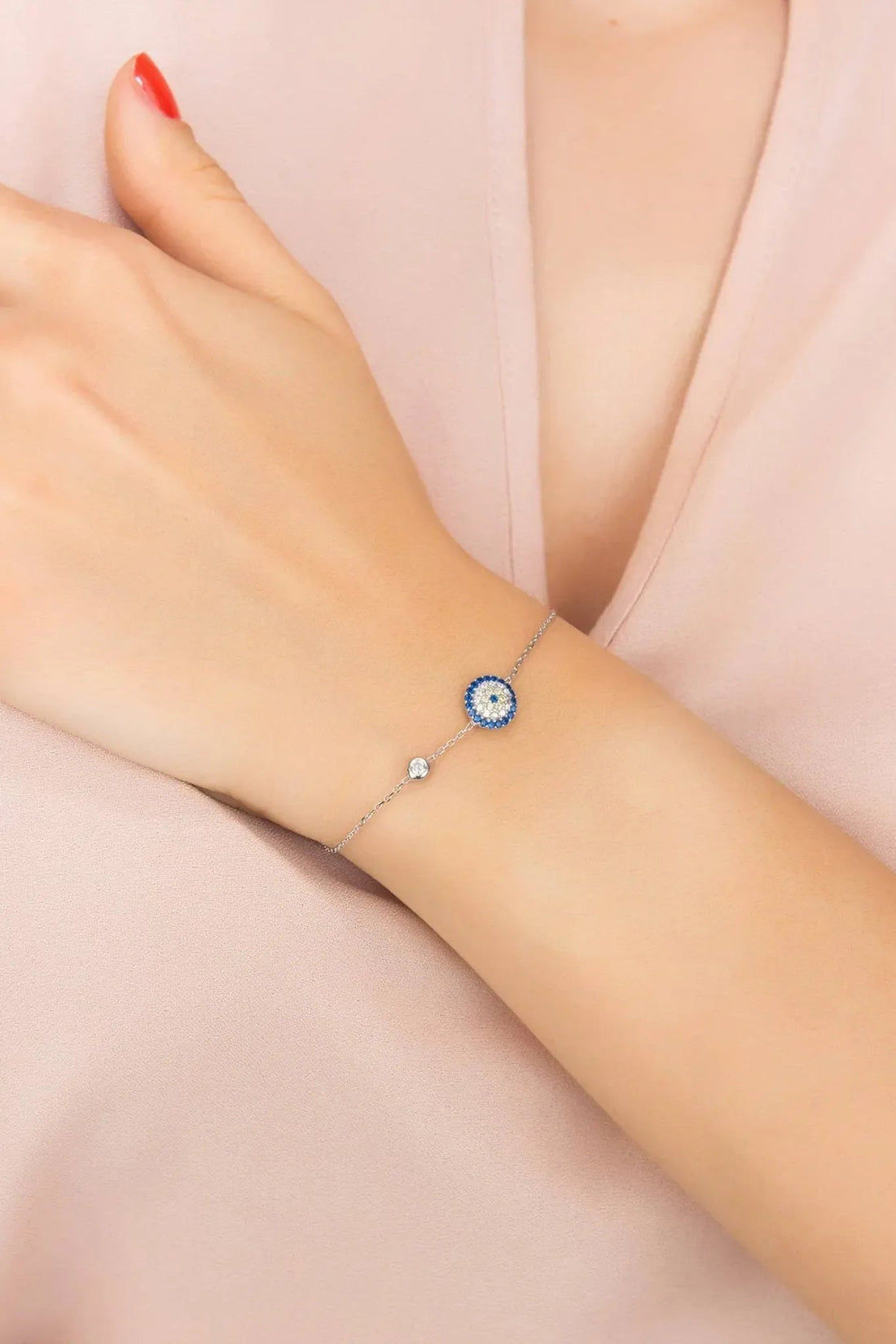 Silver chain evil eye bracelet on wrist with blue round charm