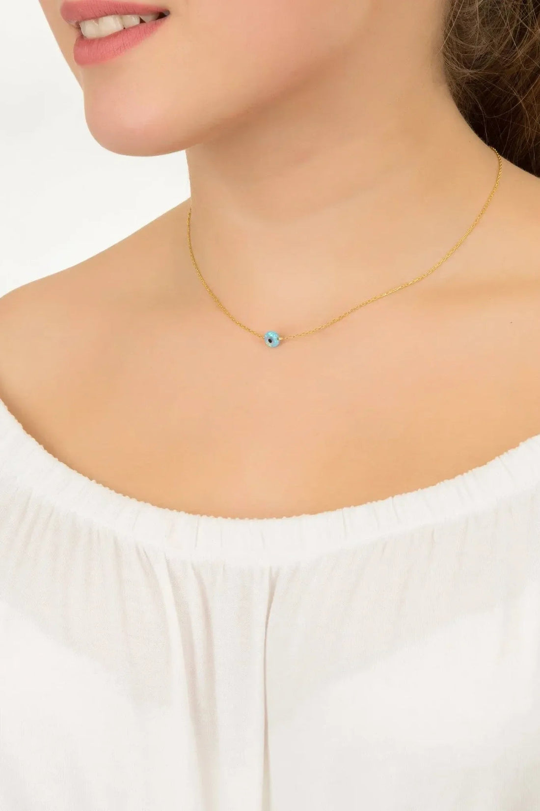 Gold evil-eye pendant necklace on model, small round blue opalite charm