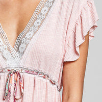 Blush striped blouse close-up with V-neck lace trim and gathered tie peplum waist