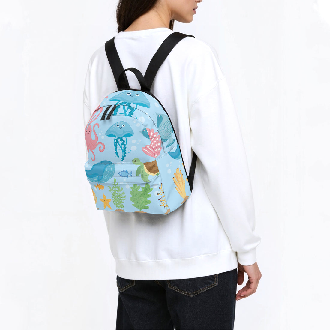 Kids backpack worn on back, blue sea creatures print with black shoulder straps.