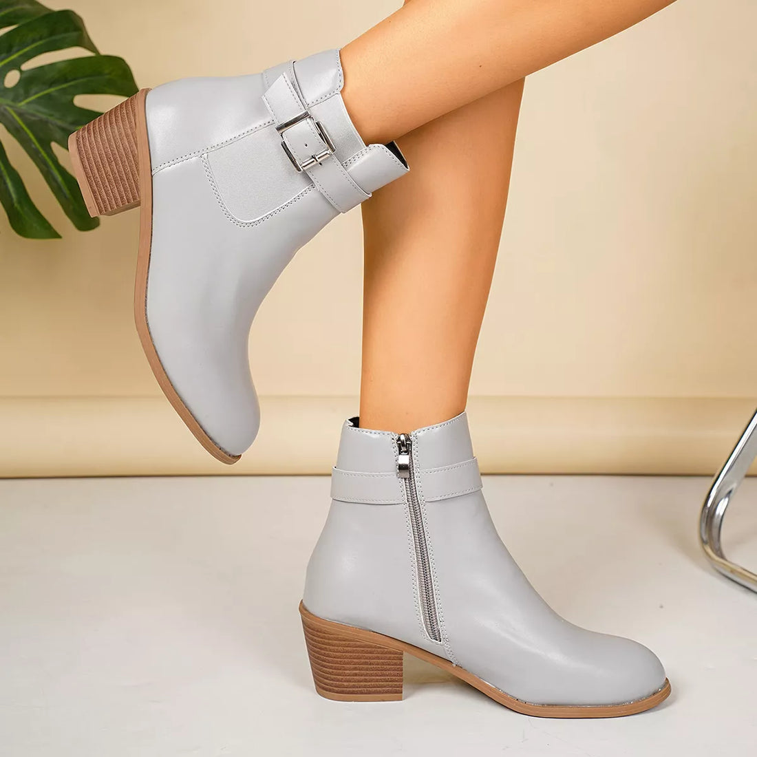 Light gray point-toe block heel boots with wide buckle strap and side zipper