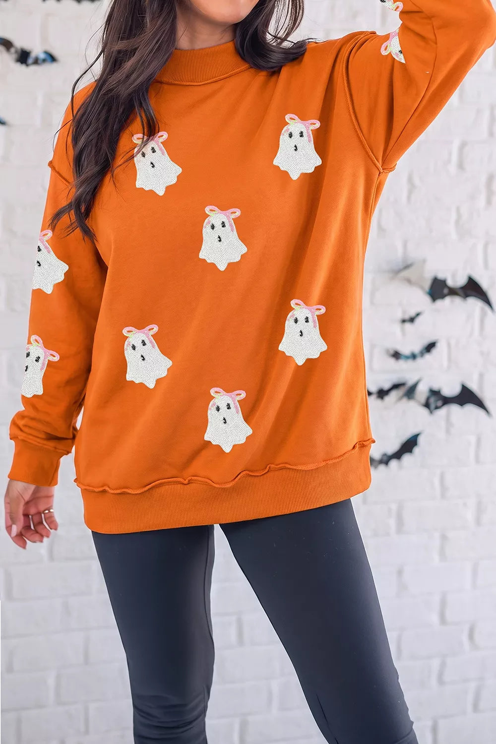Orange mock neck sweatshirt with white ghost appliques and ribbed cuffs