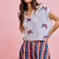 Off-white dolman sweater top featuring multiple ribbon bows over a knit texture