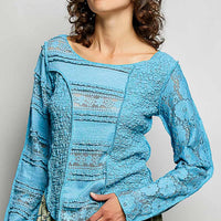 Teal blue lace long-sleeve top with exposed seams and round neckline, close-up