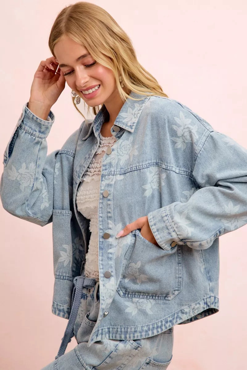 Light blue washed denim jacket with white floral print and front pockets, side view