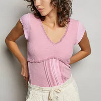 Soft pink textured knit V-neck top with lace trim and short sleeves, angled view