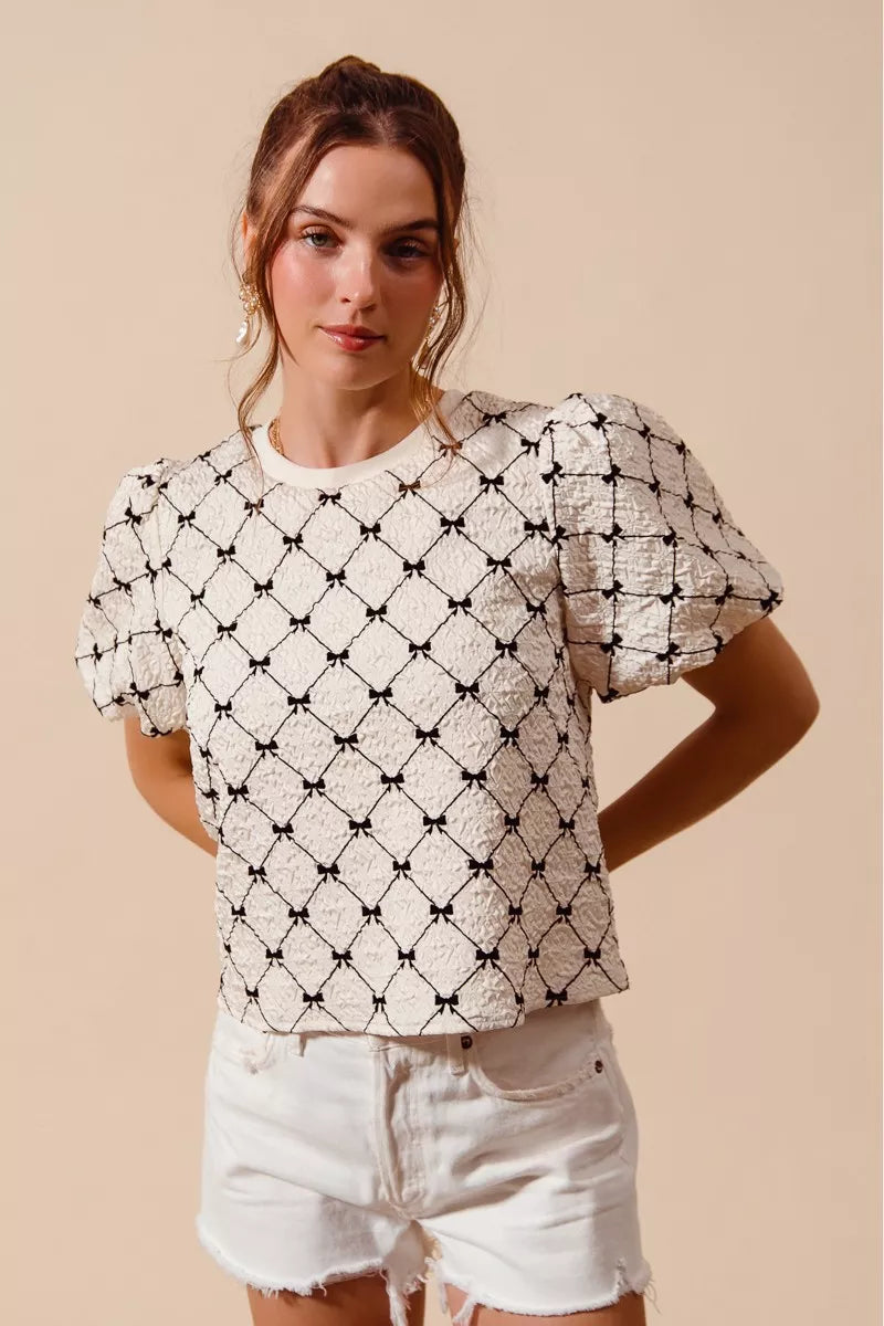 Ivory woven bubble sleeve top with black bow texture pattern, round neckline