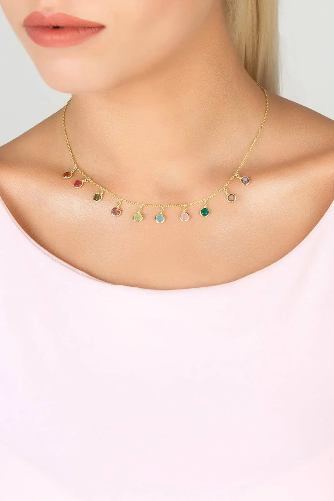 Gold multi-colored gemstone necklace worn on neck, round colored stones on chain