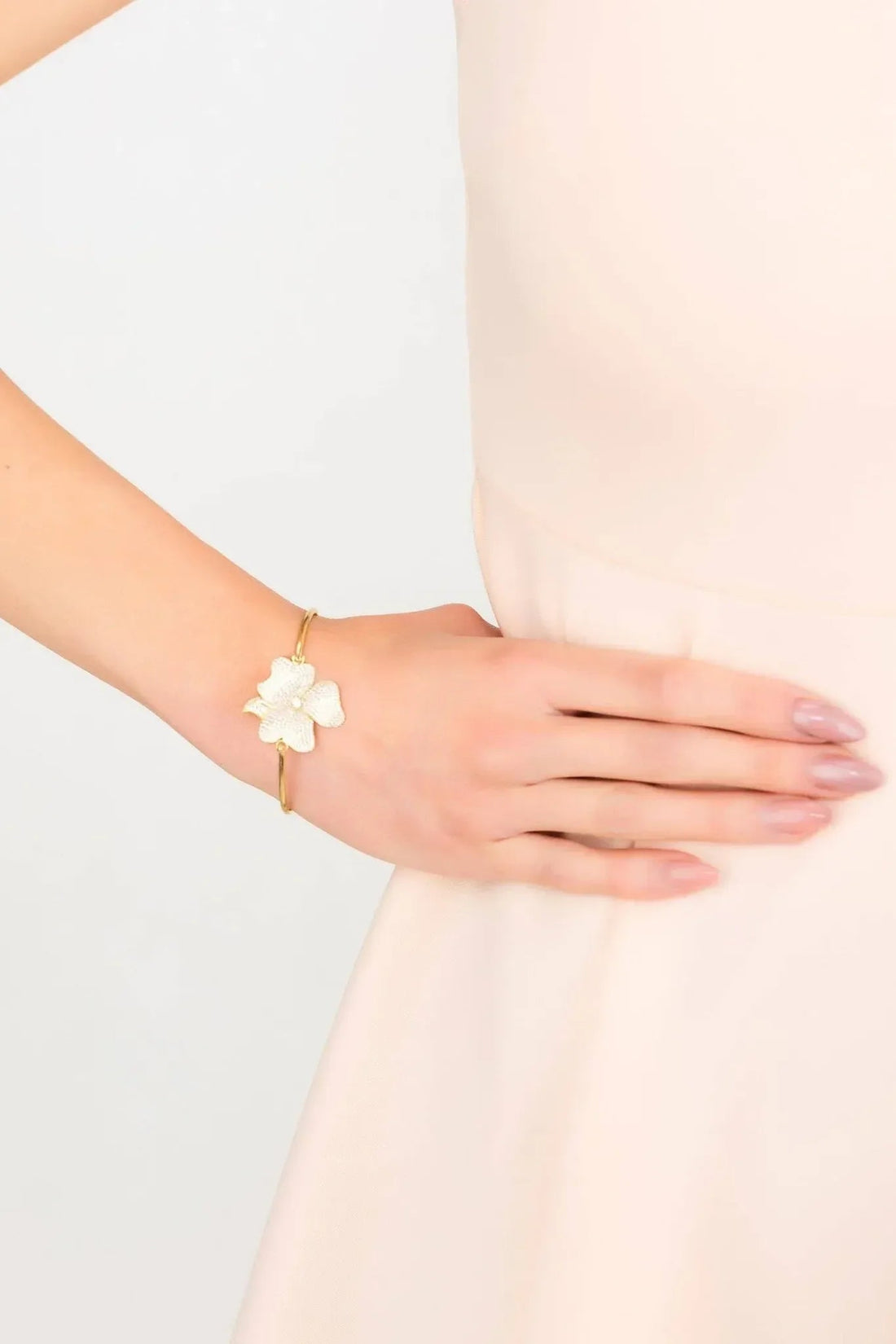 Gold bracelet on wrist with small white flower cluster