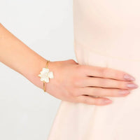 Gold bracelet on wrist with small white flower cluster