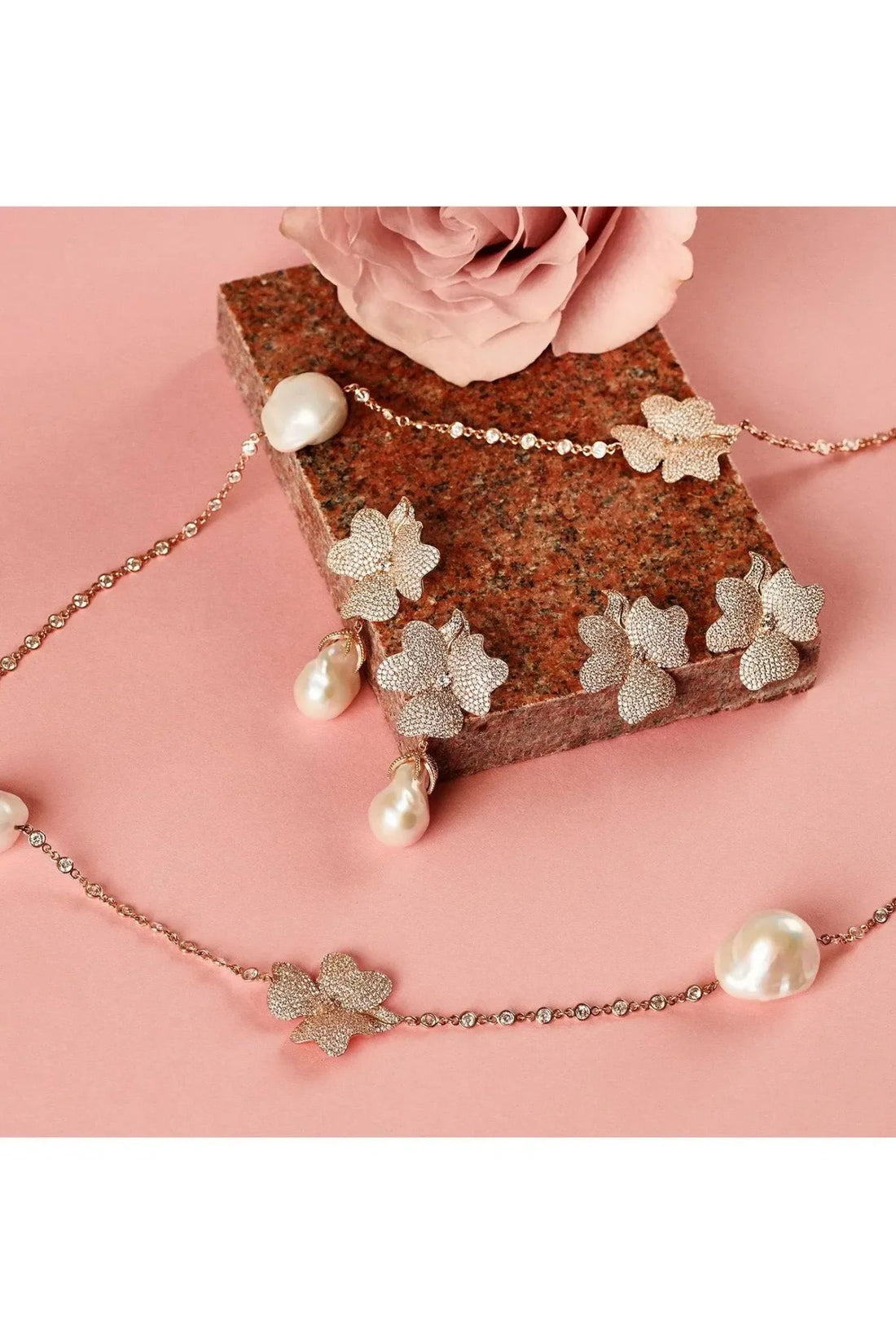 Rose-gold tone flower charm jewelry with pearl accents and dangling petals