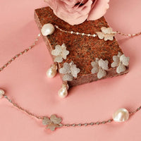 Rose-gold tone flower charm jewelry with pearl accents and dangling petals