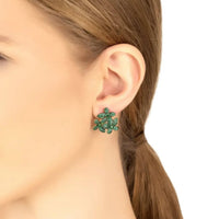 Emerald-green flower stud earrings with gold-tone posts on an ear