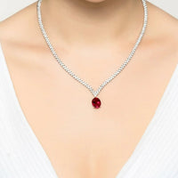 Silver tennis necklace with ruby oval pendant centered on a rhinestone chain