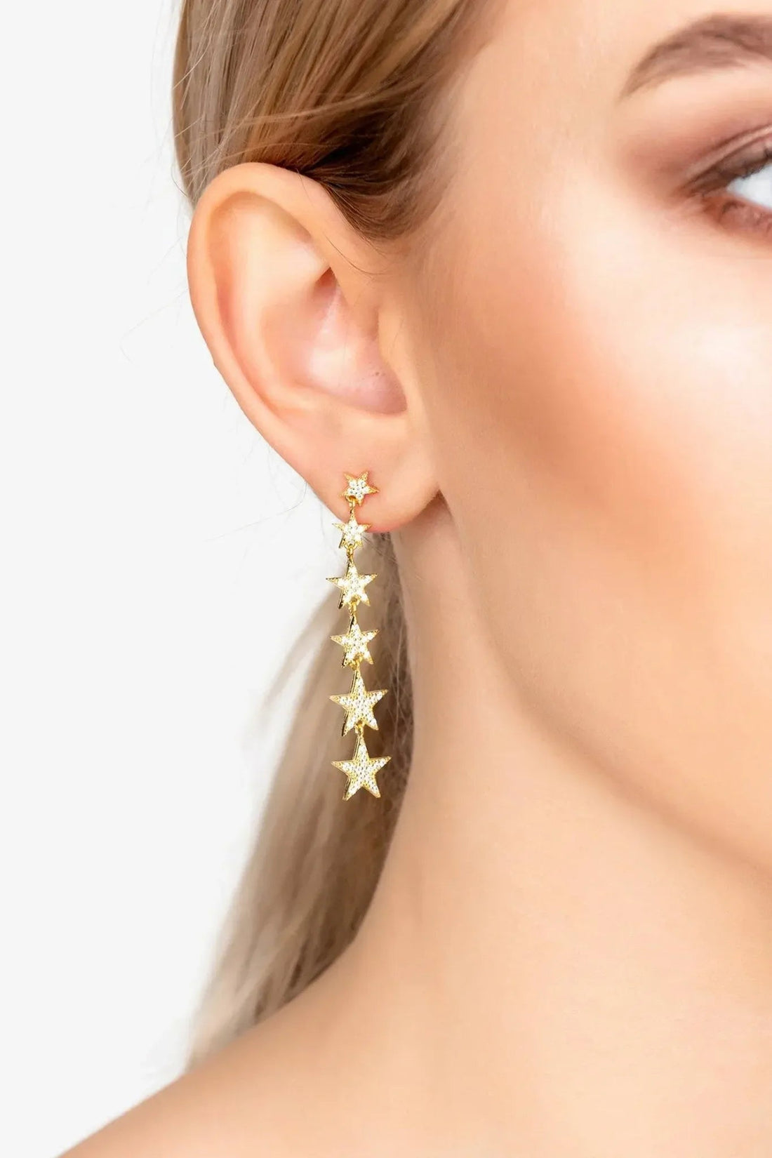 Gold star drop earrings with five star charms, seen from side