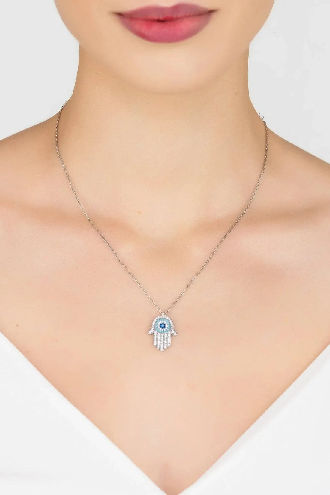Hamsa evil eye pendant necklace on neckline, silver chain with turquoise eye