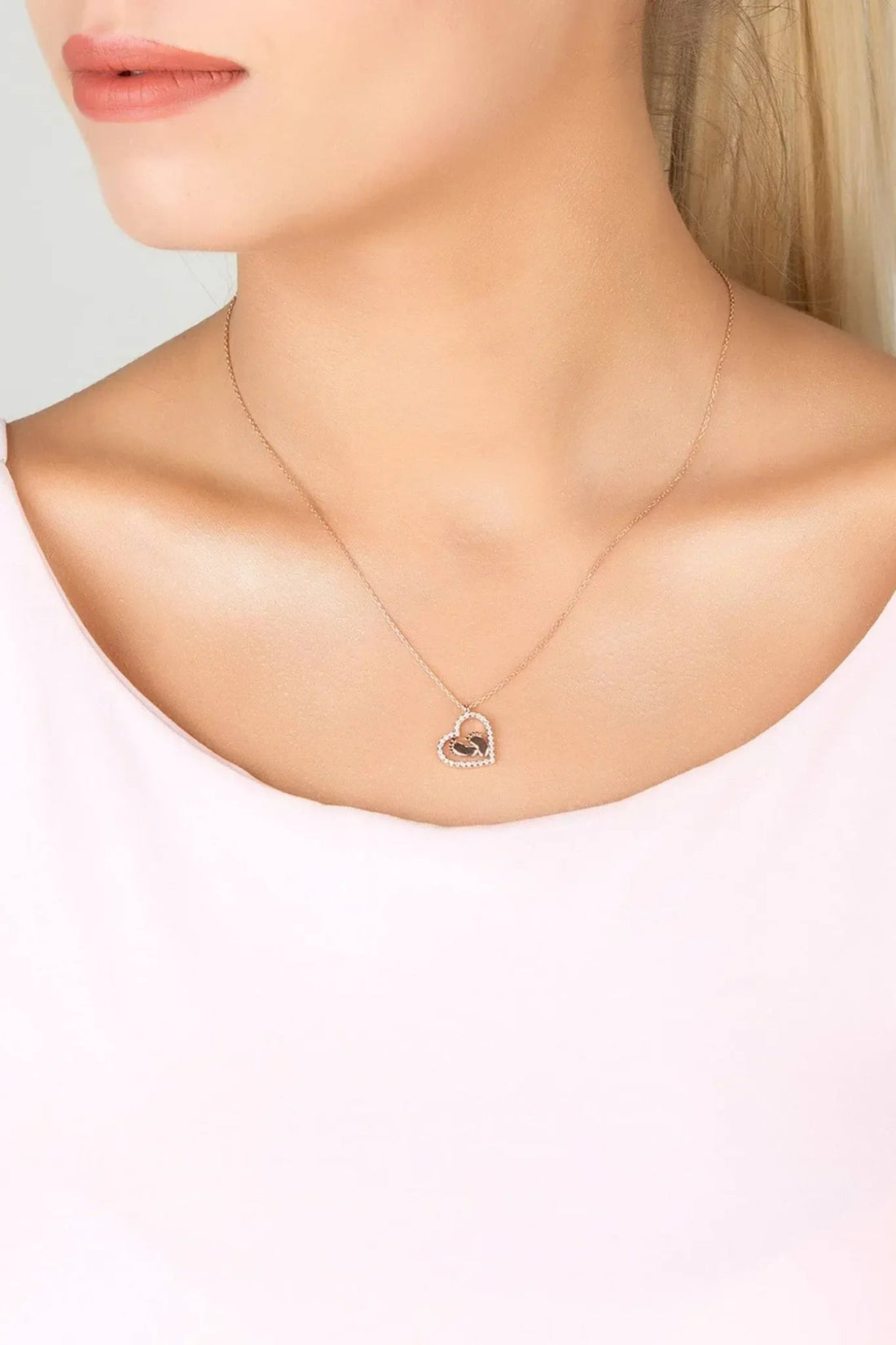 Silver heart pendant necklace worn on a neckline with small mum handprint charm.