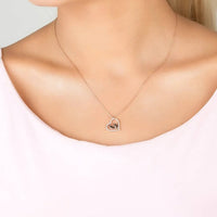 Silver heart pendant necklace worn on a neckline with small mum handprint charm.