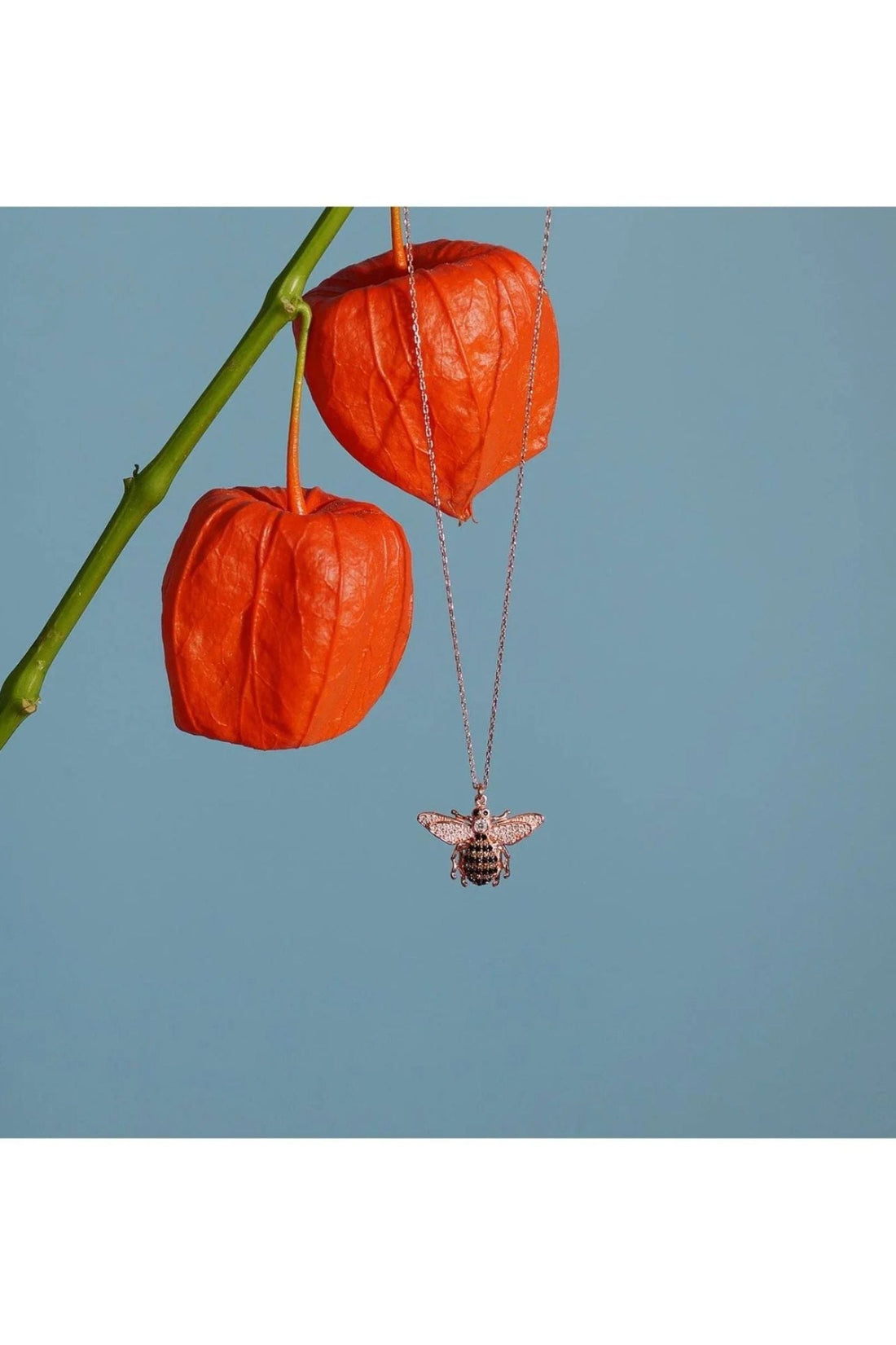 Gold-tone honey bee pendant necklace hanging from a thin chain