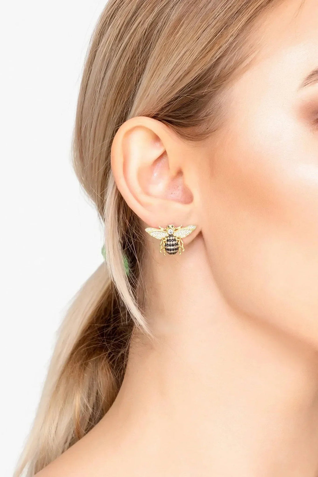 Gold honey bee stud earrings worn on ear, crystal wings and black enamel body
