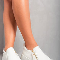 White slip-on trainers with side zipper detail and gold-tone accents, low platform sole