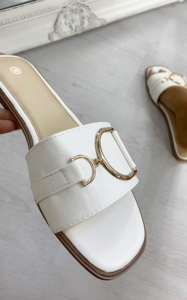 White slide sandals with wide straps and gold tone ring buckle detail
