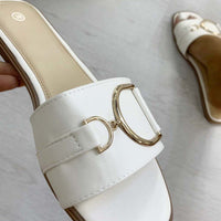 White slide sandals with wide straps and gold tone ring buckle detail