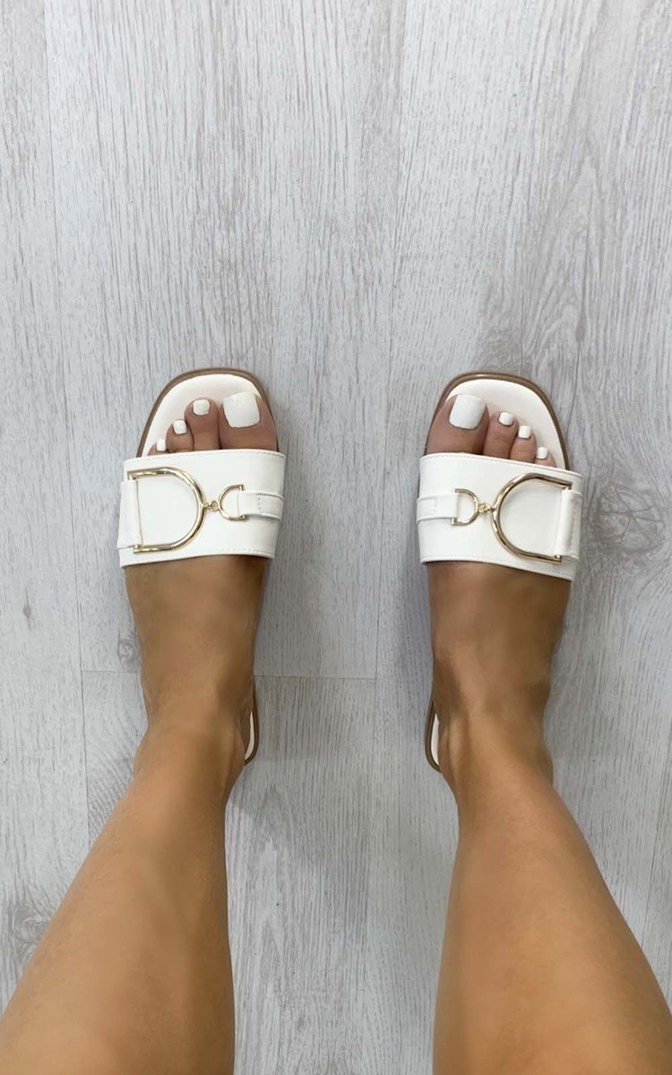 White slide sandals with wide straps and gold-tone ring detail