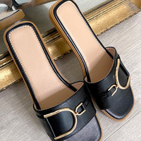 Black slide sandals with wide straps and gold-tone ring buckle detail