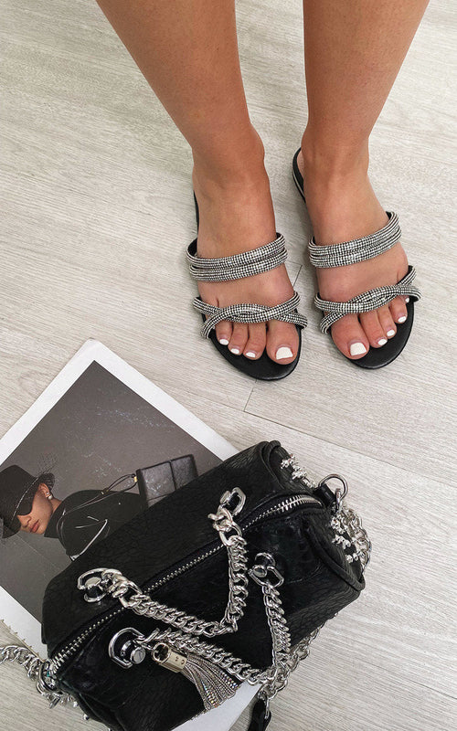Black flat slip-on sandals with silver woven straps and open-toe design