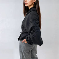 Oversized black hoodie with ruched sleeves, pouch pocket, and drawstring hood