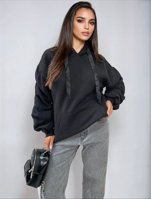 Black oversized hoodie with drawstring hood, front pouch pocket, and ruched sleeves