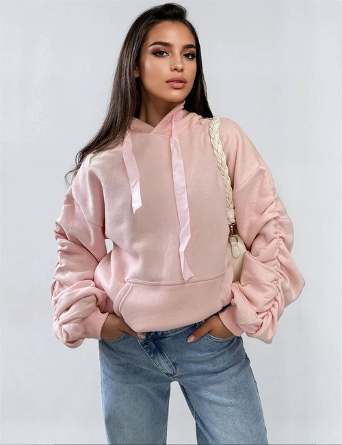 Light pink oversized hoodie with drawstring hood, front pouch pocket, and ruched sleeves
