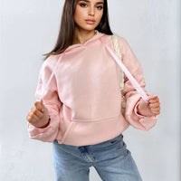 Oversized pink hoodie with ruched sleeves, pouch pocket, and drawstring hood
