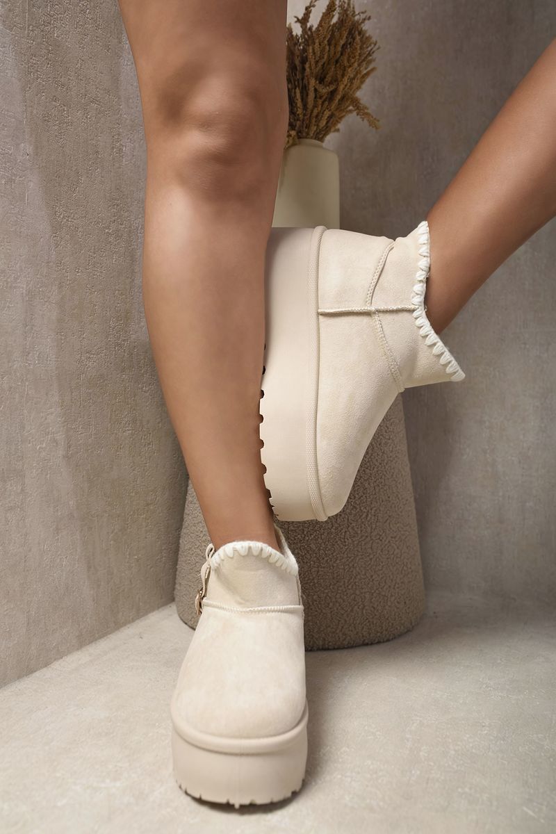Cream suede ankle boots with faux fur lining, side buckle strap, and chunky platform sole.