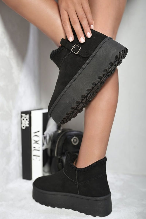 Black suede ankle boots with faux fur lining, buckle strap, and chunky platform sole.