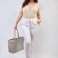 White drawstring tapered trousers with side pockets and cuffed ankle hem