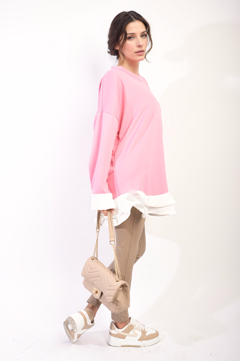 Pink oversized long-sleeve top with white ruffle hem, side view