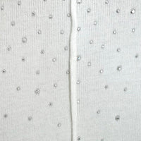 White knitted fabric close-up with rhinestone button-like specks and center seam