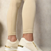 Light beige platform trainers with side zip and rhinestone front, gold-trim sole