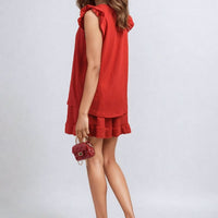 Red sleeveless ruffle-trim top and tiered shorts set, side profile.