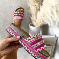 Platform slide sandals with pink woven straps, silver trim, and embellished braided edges