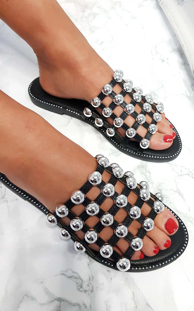 Black flat slide sandals with silver studded lattice straps and open toe