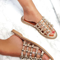 Nude flat slide sandals with studded lattice straps and sparkling rhinestone details