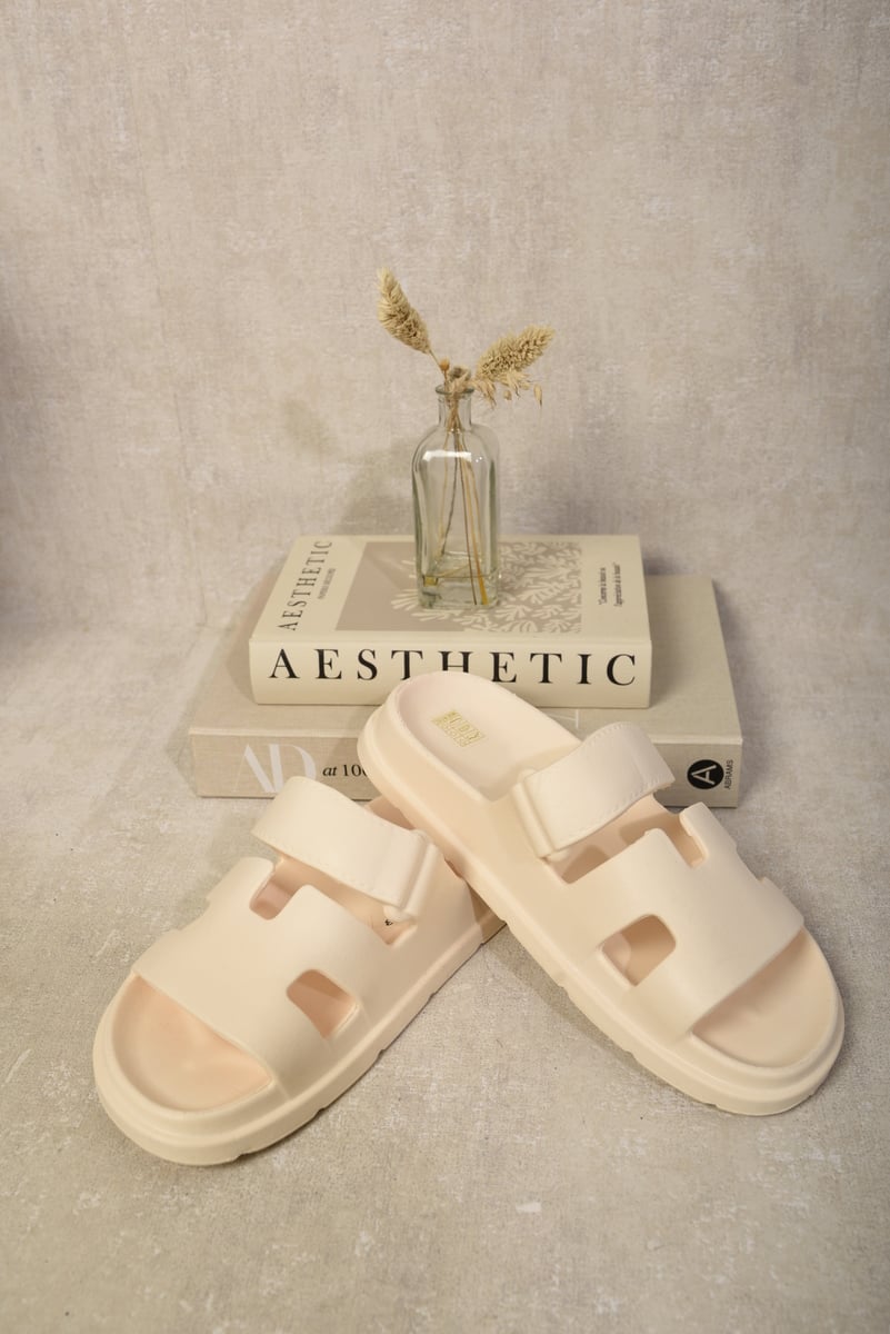 White slide sandals with geometric straps and cutout openings