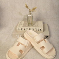 White slide sandals with geometric straps and cutout openings