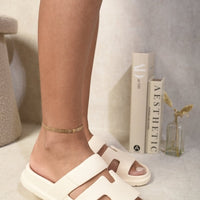 White slide sandals with geometric cutout straps and open toe
